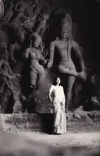 A woman stands in front of sculptures in the Elephanta Caves