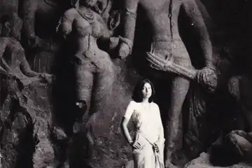 A woman stands in front of sculptures in the Elephanta Caves