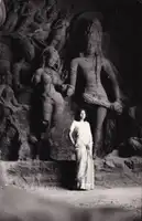 A woman stands in front of sculptures in the Elephanta Caves