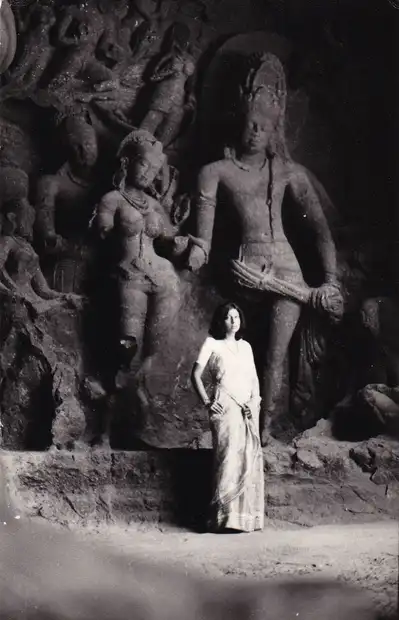 A woman stands in front of sculptures in the Elephanta Caves