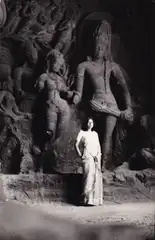 A woman stands in front of sculptures in the Elephanta Caves
