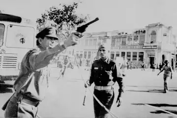 Police officer fires warning shots to disperse violent protesters after former Prime Minister Indira Gandhi is arrested and expelled from Parliament