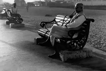 An old man sits on a bench during his morning walk along the Marine Drive, Bombay